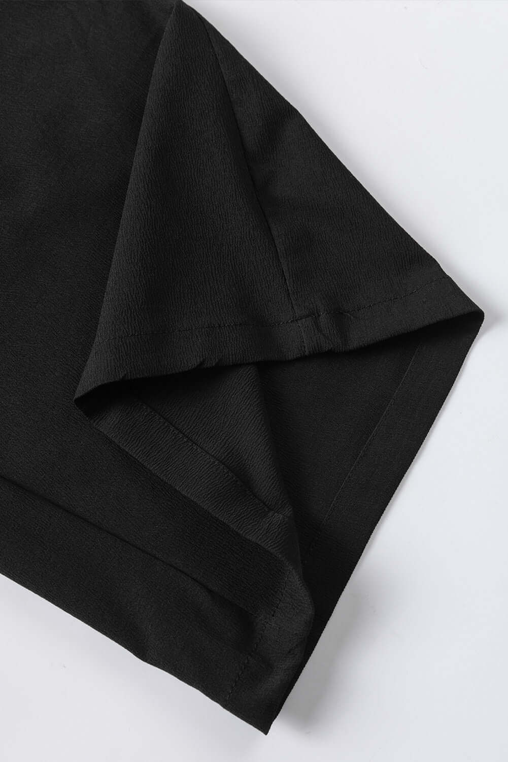 Close-up of the folded sleeve of a black shirt showcasing the fabric texture and stitching details.