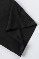 Close-up of the folded sleeve of a black shirt showcasing the fabric texture and stitching details.