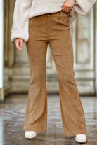 High waist brown corduroy flared pants with a checkered pattern, worn with a cozy sweater, showcasing a retro-inspired style.