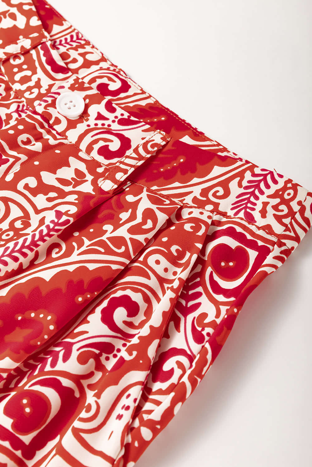 Close-up of Boho Glam wide leg pants featuring red and cream abstract pattern and button detailing.