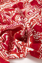 Close-up of red and cream abstract fabric showcasing a boho chic pattern for stylish wide leg pants.