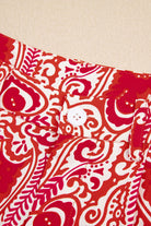 Close-up of Boho Glam Wide Leg Pants button and abstract red & cream fabric design.