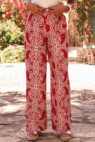 Boho glam wide leg pants in red and cream abstract pattern, featuring high waist and tailored button detailing.