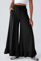 Black wide leg pants with ruffled hem and high waist, styled for comfortable, casual fashion, perfect for any occasion.
