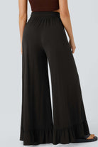 Back view of Charmed Comfort Wide Leg Pants in black, featuring a ruffled hem and elastic waistband for trendy style.