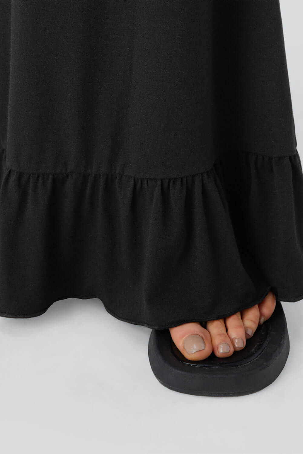 Close-up of black wide leg pants with ruffled hem and footwear, showcasing stylish comfort and feminine detail.