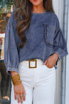 Woman wearing a stylish denim blouse with 3/4 sleeves and a chest pocket, paired with white pants and bangles.