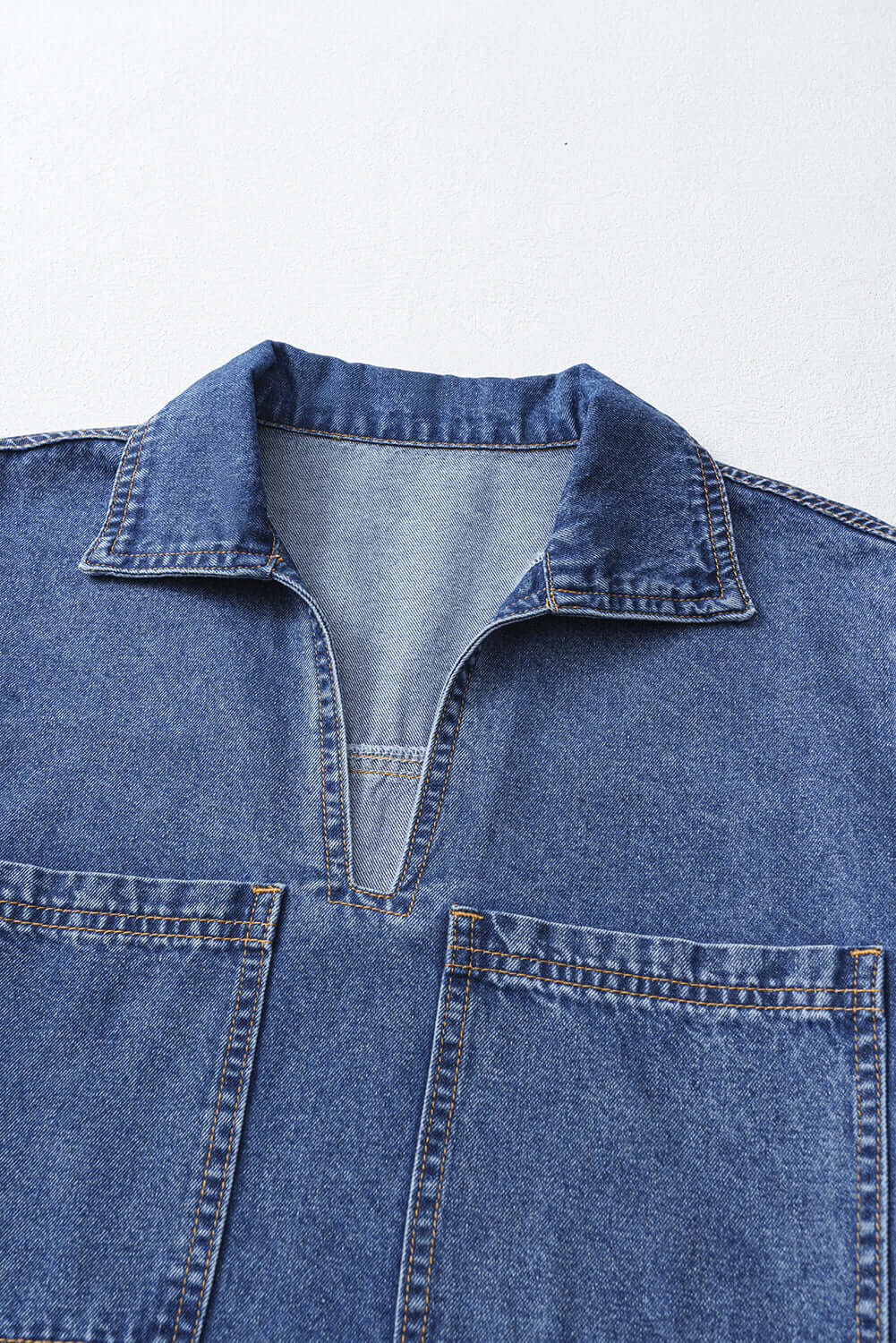 Close-up of the Blue Jean Breeze Dress collar and V-cut front with oversized pockets in denim fabric.