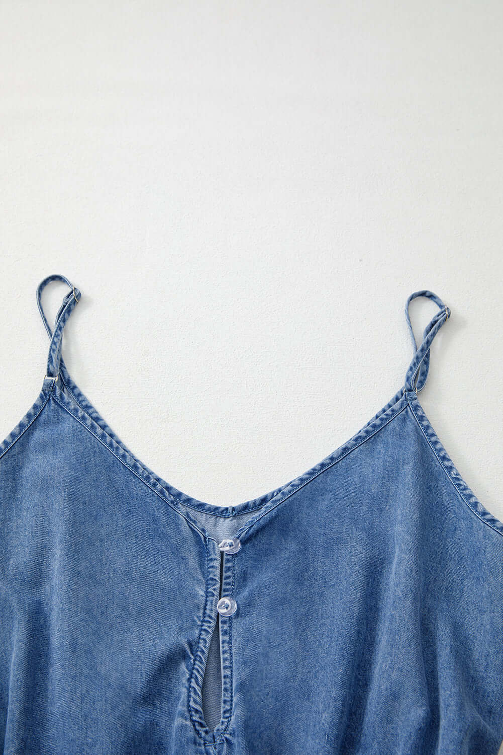 Close-up of the Shore Thing Denim Romper's V-neckline and button detail in a medium blue wash.