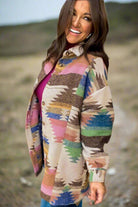 Woman wearing vibrant Aztec print PAINTED DESERT Jacket outdoors, adding cultural richness and style to her outfit.