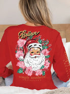 Woman wearing red Simply Southern Santa Floral long sleeve tee with Believe design, featuring festive Santa and floral print.