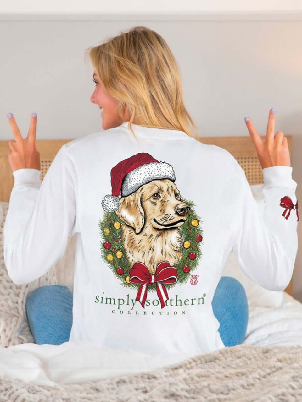 Woman wearing a Simply Southern long sleeve shirt with a dog in a Santa hat and Christmas wreath, featuring 'Always Be Merry and Bright' slogan.