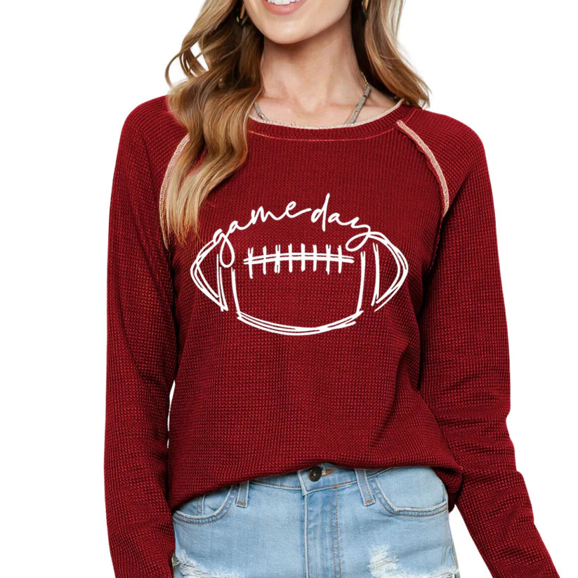 Woman wearing red waffle knit KICKOFF TIME TOP with football design, ideal for game day, showcasing sporty raglan sleeves.