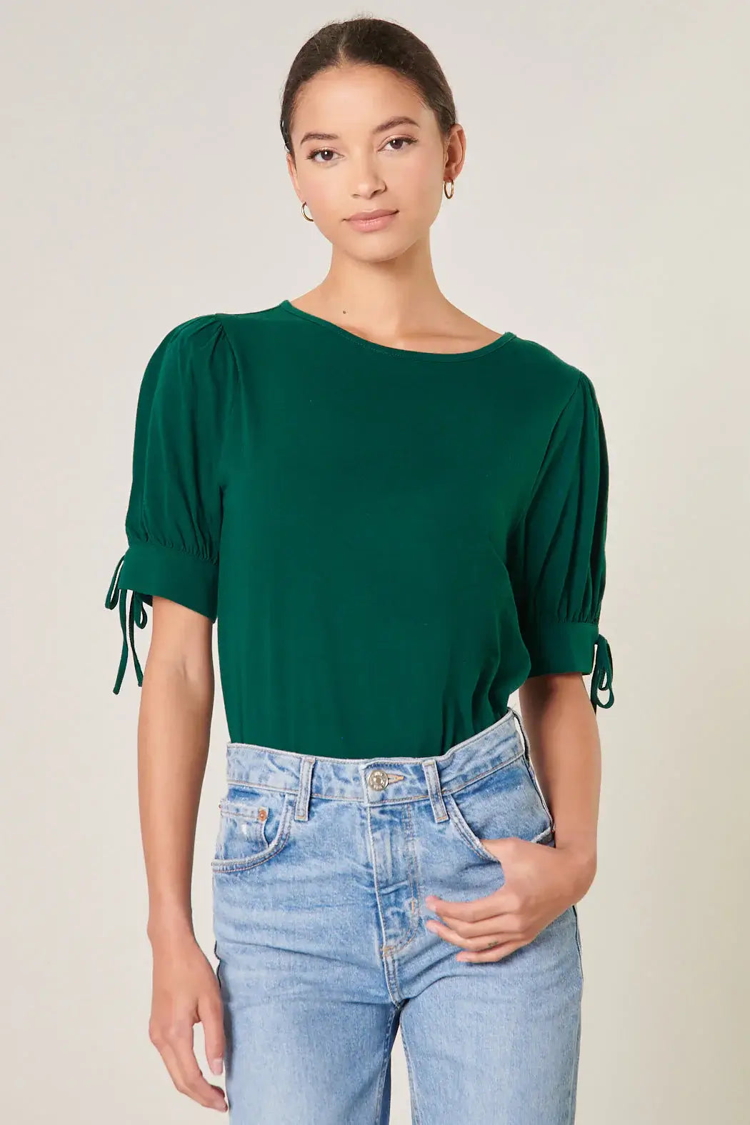 Model wearing emerald green EMERALD ENCOUNTERS TOP with puff sleeves and denim shorts.