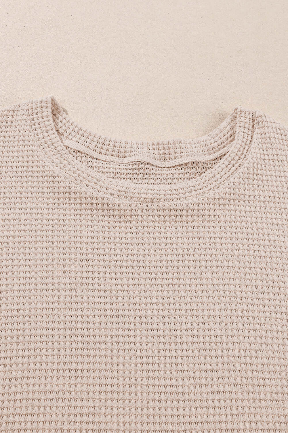 Close-up of the textured knit fabric of a beige plus size top featuring a relaxed neckline.