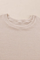 Close-up of the textured knit fabric of a beige plus size top featuring a relaxed neckline.