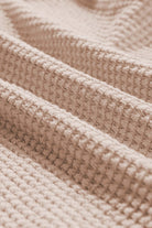 Close-up of textured beige fabric showcasing a knit pattern, ideal for fashion and textile applications.