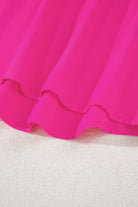 Close-up of the Berry Brilliance hot pink top's high-low hemline, showcasing its vibrant color and flowing fabric.
