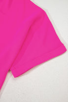Detail of the hot pink Berry Brilliance top showcasing cuffed sleeves on a light background.