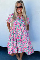 Model wearing Heirloom Blooms Dress with vibrant pink floral print and puff sleeves, perfect for spring and summer.