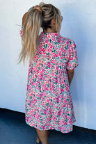 Model wearing the Heirloom Blooms Dress, showcasing vibrant pink floral print and tiered skirt from the back.