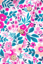 Close-up of the vibrant pink floral print and buttons on the Heirloom Blooms Dress fabric.