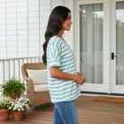 Model wearing the UNSTOPPABLE YOU TOP (aqua) with a striped pattern, showcasing stylish comfort on a porch.