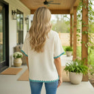 Woman wearing the CONFIDENT SPIRIT TOP - Umgee with playful ric rac trim, showcasing effortless style in a serene outdoor setting.