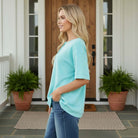 DAILY GO-TO TOP - Andree' in a relaxing outdoor setting, featuring a stylish blue short sleeve top with pockets.