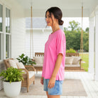 Model wearing FEEL GOOD FAVE TOP - Andree' (pink) on a porch, showcasing its casual and comfortable style.