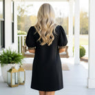 Woman wearing the BOLD MOVES DRESS, showcasing a black design with leopard trim and a sleek silhouette.