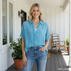 A woman wearing the CALMING COAST TOP - Umgee in aqua, styled with jeans in a bright outdoor setting.