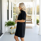 Model wearing BOLD MOVES DRESS with leopard trim, showing off the stylish zip-up collar on a porch.