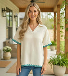 CONFIDENT SPIRIT TOP - Umgee worn by a smiling woman with wavy hair, showcasing playful ric rac trim in a stylish setting.