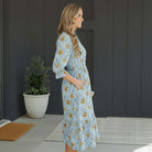 Side view of a woman wearing the LIMITLESS LIVING MIDI DRESS with floral print and pockets, showcasing effortless elegance.