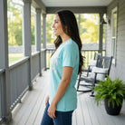 LULU MAC MINERAL AQUA & CAMO COMFORT COLOR TEE worn by a smiling woman on a porch, showcasing its soft fabric and relaxed style.