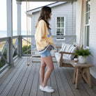 LULU MAC SOCIAL SOCIETY CREW (Butter/Cornflower) worn by a woman outdoors on a porch, styled with denim shorts.