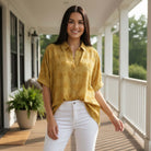 Model wearing DOT DIRECTIONS TOP - Umgee (gold) with polka dots, styled casually with white jeans.