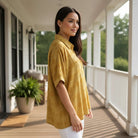 Stylish woman wearing the DOT DIRECTIONS TOP - Umgee (gold) on a porch, featuring classic polka dot design.