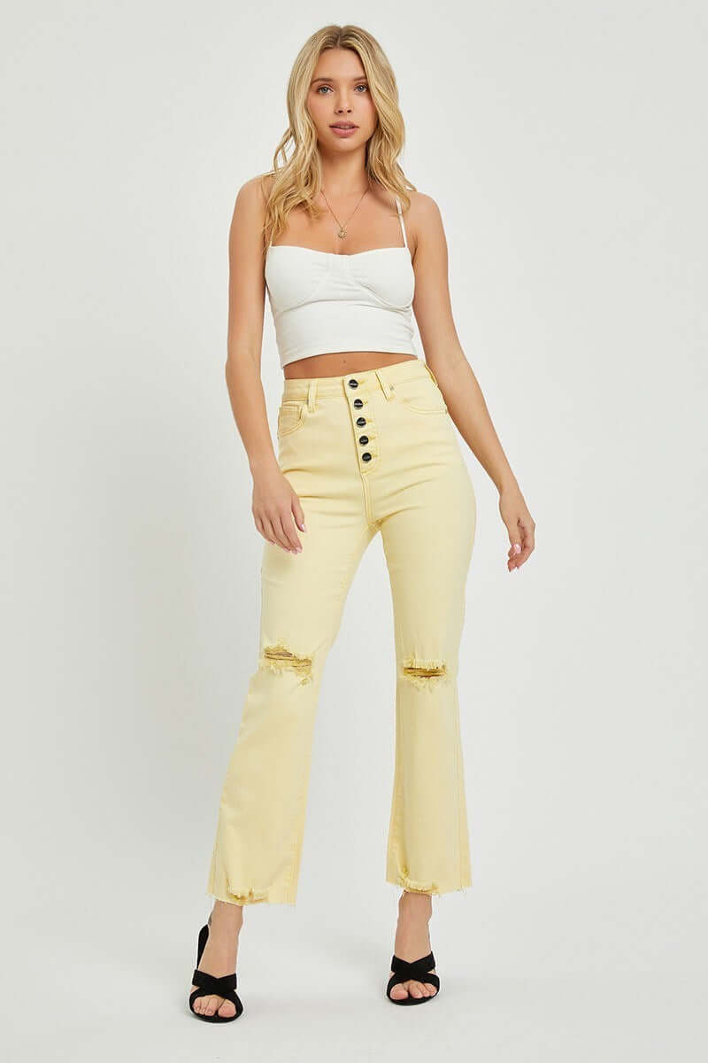 Model wearing Risen Sunny Girl high-rise pale yellow denim jeans with a cropped top and heels.