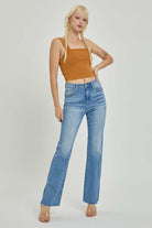 Model showcasing SHILO Bootcut Jeans by Risen, featuring a high rise, medium wash, and raw cut hem in a stylish pose.