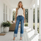 Model wearing RISEN GIANNA JEANS paired with a white tank top, showcasing a stylish relaxed fit on a porch.