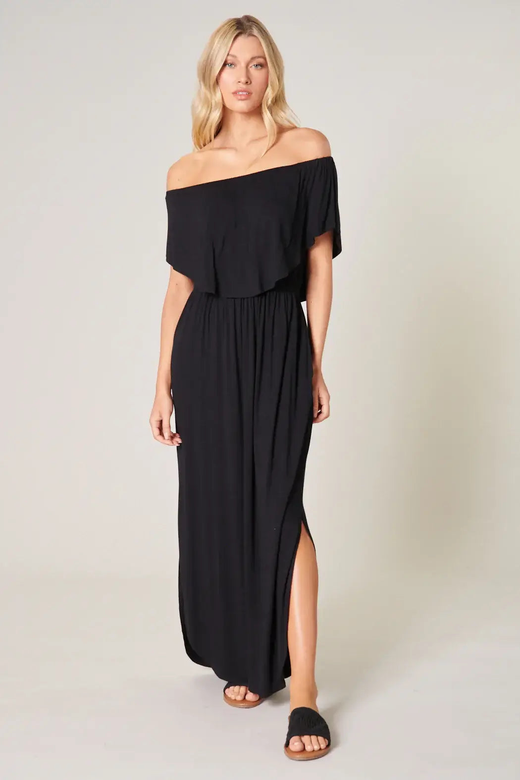 Woman in black off-shoulder Midnight Flow Maxi Dress, featuring pockets and side slit detail, styled for a chic look.