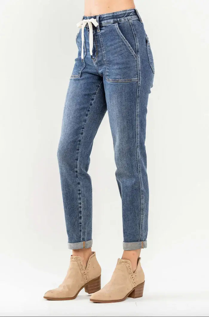Judy Blue Janie Plus Size Joggers in medium wash with cuffed hems and elastic drawstring waist, paired with ankle boots.
