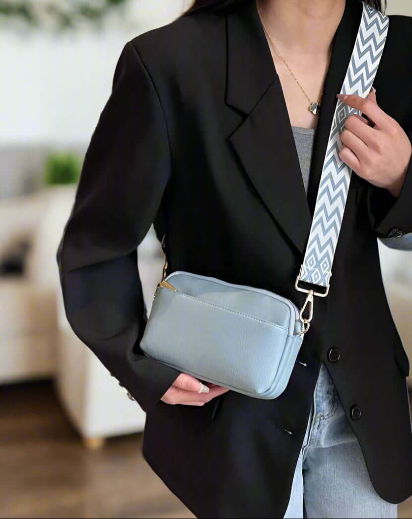 Stylish woman wearing a light blue SKYE Crossbody Bag with a patterned strap in a chic outfit.