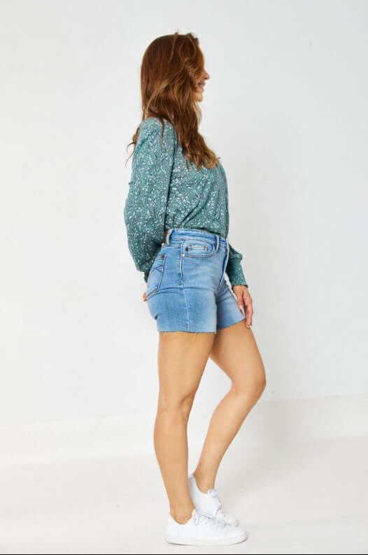 Stylish model wearing JUDY BLUE Cassidy Shorts with a green top, showcasing a trendy summer look.