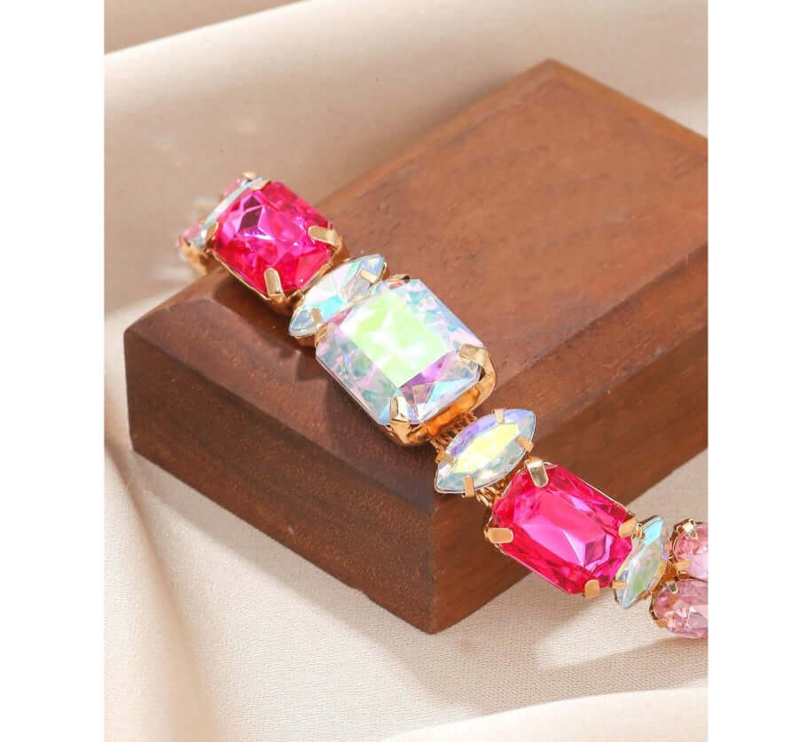 Gold-tone Sparkle Theory Bracelet with oversized pink and iridescent gems, perfect for dazzling wrist highlights.