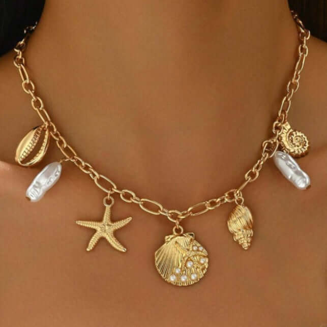 High Tide Treasures charm necklace with seashells, starfish, and faux pearls on a gold tone chain.
