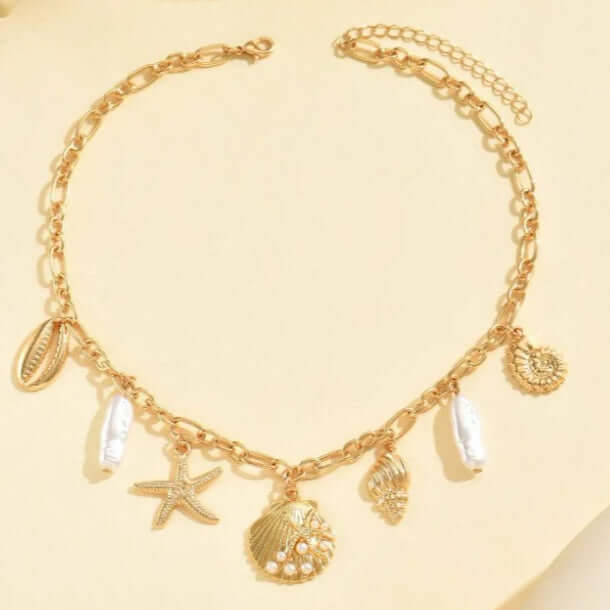 High Tide Treasures Charm Necklace with gold seashells, starfish, and faux pearl beads on a chic chain.