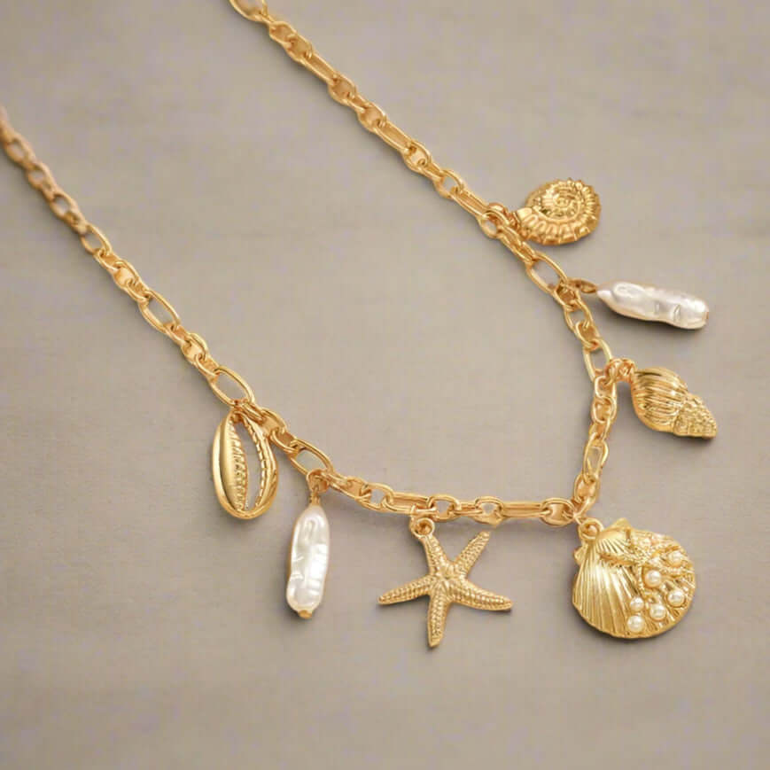 High Tide Treasures Charm Necklace with golden seashells and faux pearl beads on a gold tone chain.